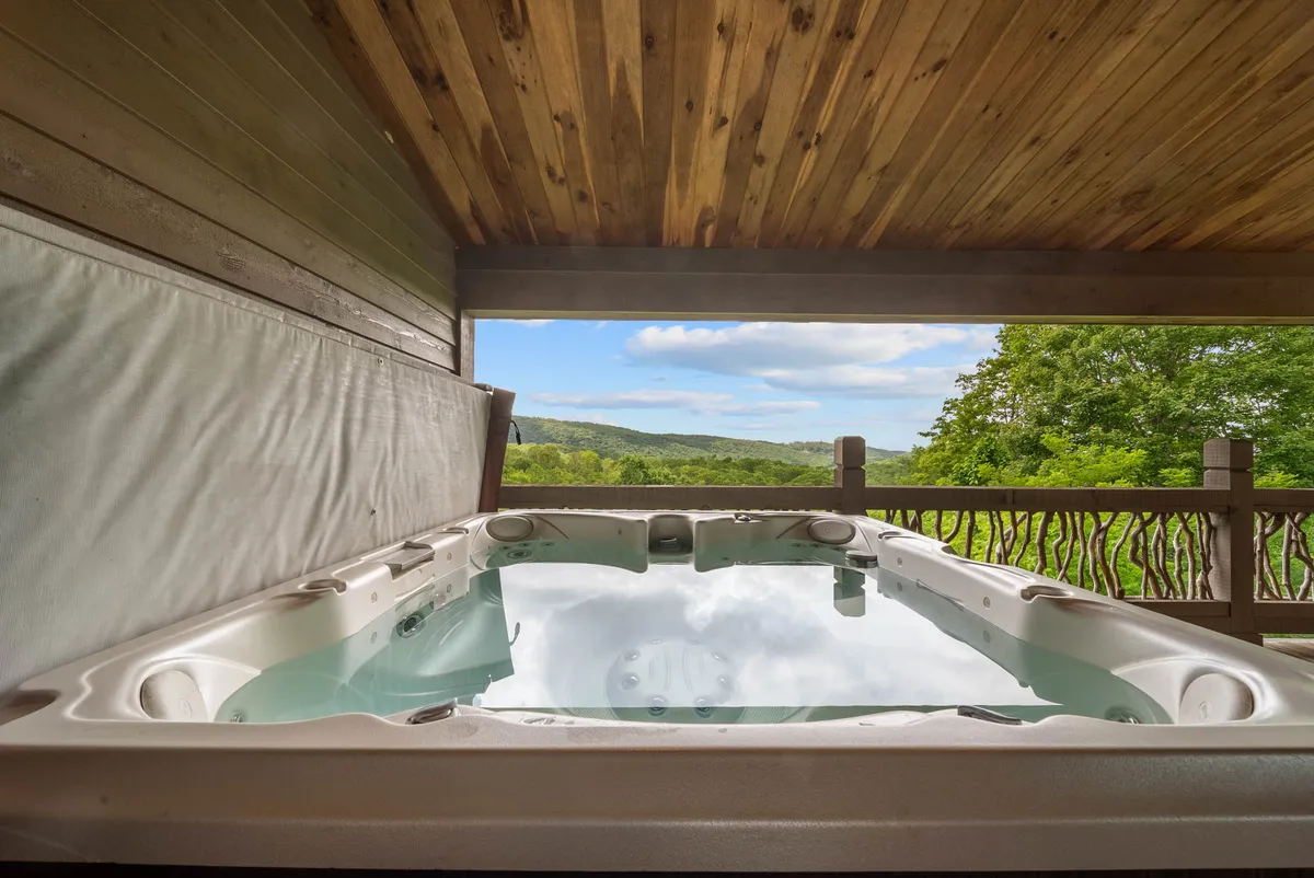 An interior hot tub is set beside large windows, offering expansive views of surrounding mountains and trees. The tranquil atmosphere encourages relaxation and immersion in nature, with the outdoors just beyond reach.