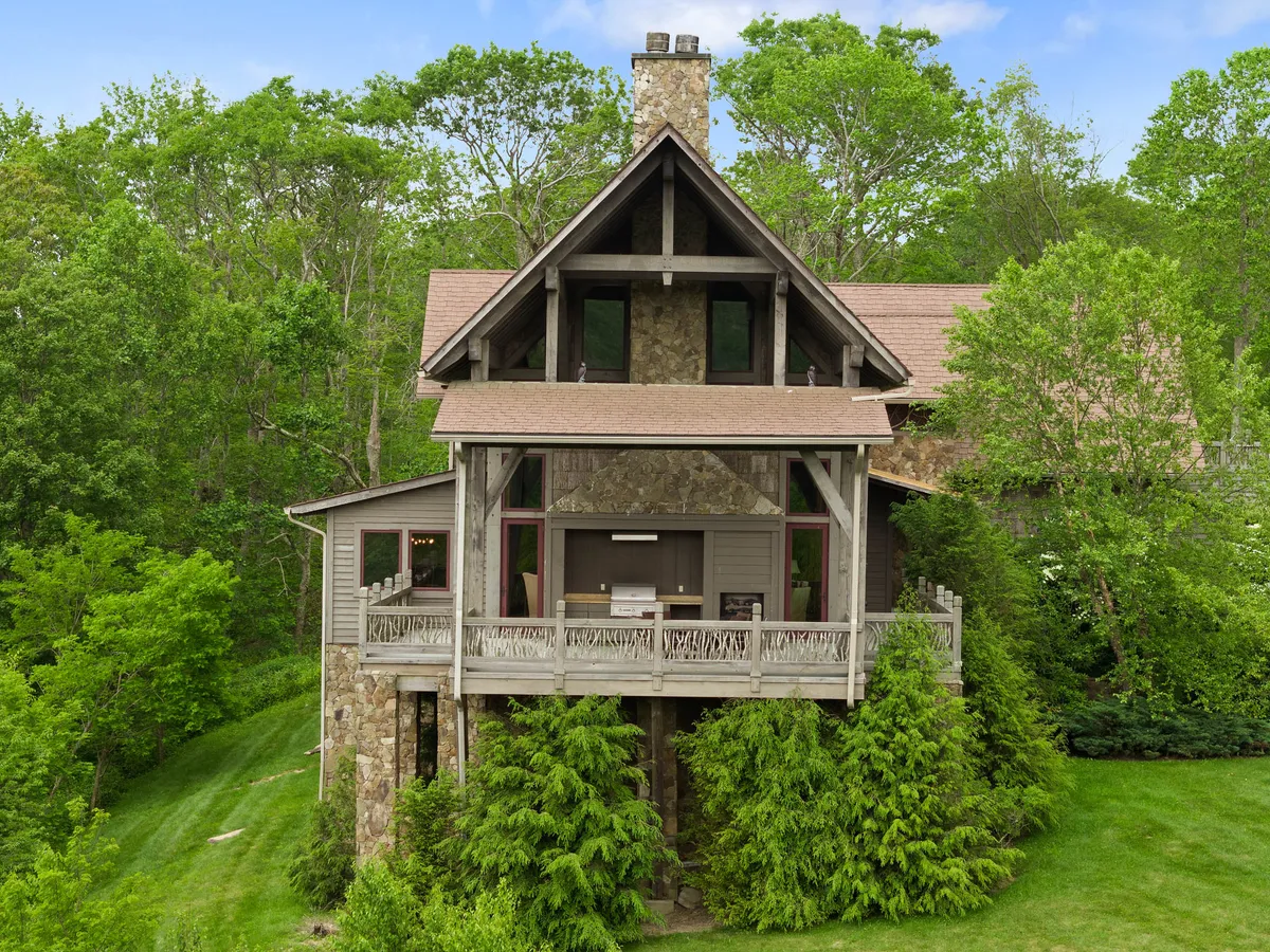 A serene exterior shot focusing on a stone facade, wooden balcony, and the surrounding greenery. The balcony is ideal for private relaxation or stargazing—an outdoor extension of the bedroom retreats, bridging indoor and outdoor serenity.